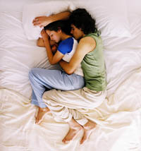 A man holding a woman from behind in bed (spoon position)